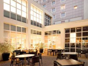 Novotel Lille Centre Grand Place في ليل: مبنى فيه طاولات وكراسي امام مبنى