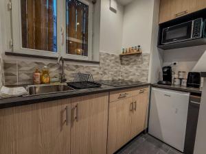 a kitchen with wooden cabinets and a sink and a microwave at T2 avec bain à remous en plein centre de Chartres in Chartres
