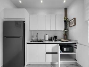 圣胡安Hyde Park 3 Comfy Apt With Parking in San Juan的厨房配有白色橱柜和黑色冰箱