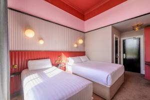 two beds in a room with red and white walls at Hotel St George by Nina in Dublin