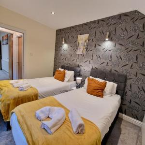 two beds in a hotel room with towels on them at Coventry Retreat - Modern 2 Bed Apartment in Spon End
