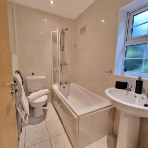 a bathroom with a tub and a toilet and a sink at Coventry Retreat - Modern 2 Bed Apartment in Spon End