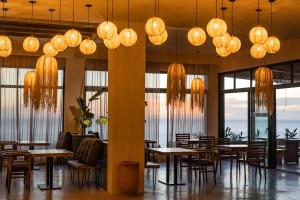 a restaurant with tables and chairs and chandeliers at Nobi Boutique Surf Hotel Taghazout in Tamraght Ouzdar