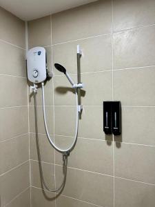 a shower in a bathroom with a hair dryer on a wall at Make Memories Escape 2BR Stay Summer Mall in Kota Samarahan