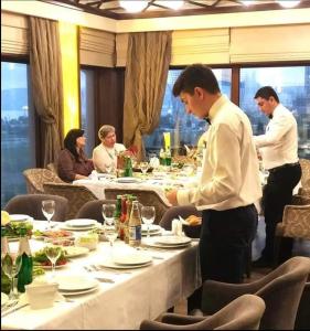 a group of people standing around a table in a restaurant at Boulevard Side Hotel in Baku