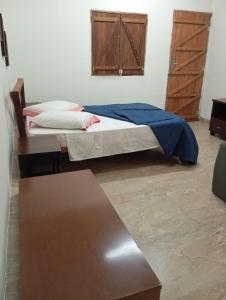 een slaapkamer met een bed met een blauwe deken erop bij Pousada Encanto dos Olhos in Alexânia