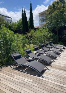 een rij ligstoelen op een houten terras bij Beautiful house Ciboure pool designed in Ciboure