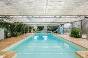 a swimming pool with a slide in a building at Maison Percheronne by Green Folies, 15p & piscine in La Gaudaine
