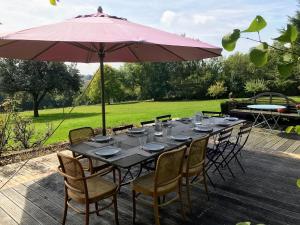 a table with chairs and an umbrella on a patio at Maison Percheronne by Green Folies, 15p & piscine in La Gaudaine