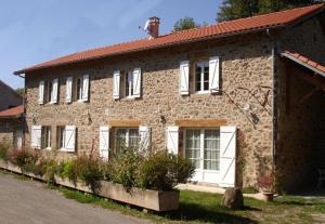 Una gran casa de ladrillo con puertas y ventanas blancas. en Gîte lumineux, en Antaignagues