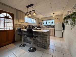 Una cocina con una barra con dos sillas y un refrigerador. en NBs Sage & Stone Nest, en Edenvale