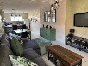 Una sala de estar con un sofá y un televisor. en NBs Sage & Stone Nest, en Edenvale
