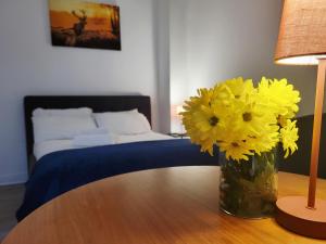 a vase of yellow flowers on a table with a bed at Cosy in Cork in Cork