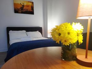 a vase of yellow flowers on a table with a bed at Cosy in Cork in Cork