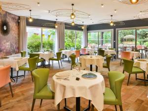 a restaurant with tables and chairs and windows at Mercure Bourg En Bresse in Bourg-en-Bresse