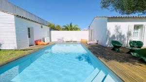 a swimming pool with a wooden deck next to a house at Superbe villa avec piscine dans le village de St Clément in Saint-Clément-des-Baleines