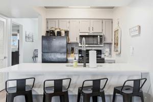 a kitchen with white cabinets and a counter with chairs at Ozark Overlook Escape - For 6 in Branson West