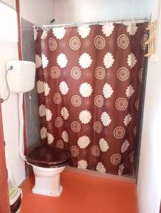 a bathroom with a toilet with a brown shower curtain at El Romance in Jaureguiberry
