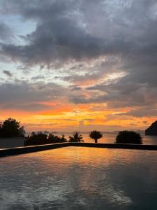 Una puesta de sol sobre una piscina con el cielo en Sunset bay view villa krabi, en Ban Khao Thong