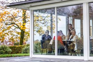 a group of people sitting at a table in a conservatory at Hotel Refsnes Gods - by Classic Norway Hotels in Moss