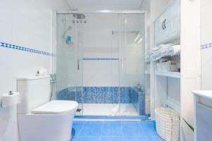 a bathroom with a toilet and a shower with blue tiles at Apartamento Deluxe 1 Room Piscina Parking LuxSevilla Bormujos in Bormujos