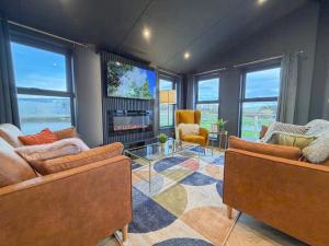 a living room with two couches and a fireplace at Blackthorn Timber Lodge in Bothel