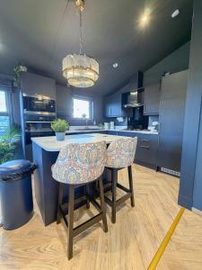 een keuken met een eiland met twee barkrukken bij Blackthorn Timber Lodge in Bothel