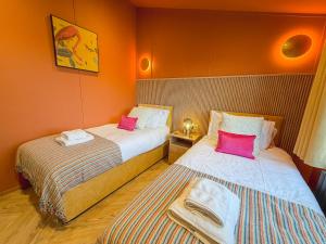 twee bedden in een kamer met oranje muren bij Blackthorn Timber Lodge in Bothel