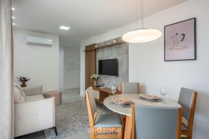 Apto a 750m do Mar c/ varanda e churrasq. GVT2105 في ميا برايا: غرفة طعام وغرفة معيشة مع طاولة وكراسي