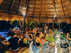 a group of people sitting at tables in a restaurant at Viajero Bacalar Hostel in Bacalar
