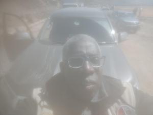 Un hombre con gafas de pie delante de un coche. en Hotel britania, en Lima