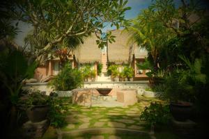 a garden with a table and trees and a building at Lulu's Wellness Boutique Villas in Uluwatu