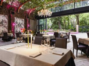a dining room with white tables and chairs and windows at Papadopoli Hotel Venezia - MGallery Collection in Venice