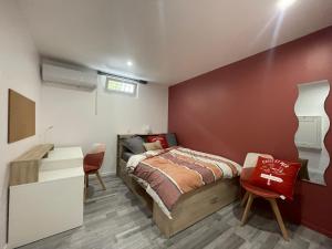 Belle Chambre tout confort indépendante pour un séjour au soleil في لا فاليت دو فار: غرفة نوم بها سرير وجدار أحمر