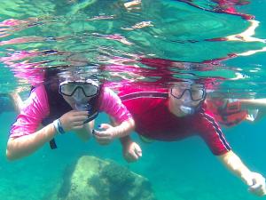 two people are swimming in the water at Club Cantamar Beach Hotel & Marina in La Paz