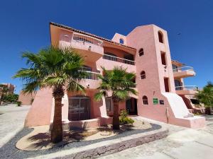 a pink building with palm trees in front of it at Club Cantamar Beach Hotel & Marina in La Paz +30 photos