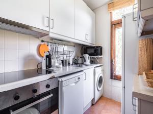 a kitchen with white cabinets and a washer and dryer at Akisol Troia Apricot in Troia