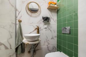 La salle de bains est pourvue d'un lavabo, d'un miroir et de carrelage vert. dans l'établissement Just Sezimbra- Modern Apt 3 Min from Beach, à Sesimbra 17 autres photos