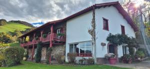 a white house with a balcony on the side of it at Ferme Ithurburia in Saint-Michel