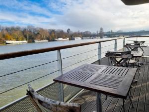 a table and chairs sitting on a deck next to the water at EXIGEHOME-Large houseboat with spa near Paris in Saint-Cloud