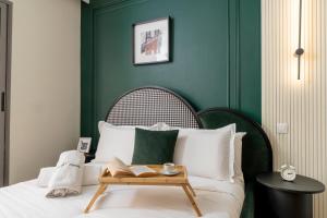 The Loft Residence by GoodMove - Maarif Casablanca في الدار البيضاء: غرفة نوم خضراء مع سرير عليه صينية خشبية