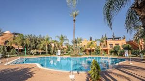 a swimming pool in a resort with a palm tree at Appartement cosy, calme, détente, piscines, jardins in Marrakech