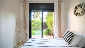 a bedroom with a bed in front of a glass door at Appartement cosy, calme, détente, piscines, jardins in Marrakech +29 photos