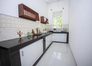 a large kitchen with white cabinets and a black counter top at Samaro Resort in Mirissa +89 photos