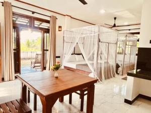 a room with a table and a bed with mosquito net at Samaro Resort in Mirissa