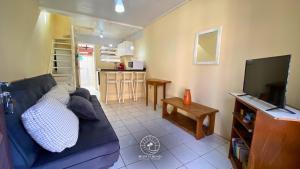 Una sala de estar con un sofá azul y un televisor. en Sobrado aconchegante próximo do mar, en Passo de Torres