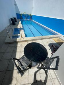 a table and chairs next to a swimming pool at Pousada Maré Alta Pajuçara in Maceió +31 photos