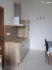 a kitchen with white walls and wooden cabinets at Douillet F1 Place Paoli in Corte