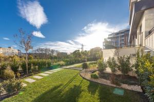 Stylish 1BR Flat Garden Balcony Parking في مدينة فارنا: حديقة بها عشب ونباتات ومبنى