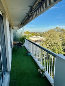 d'un balcon avec de l'herbe verte et une table. dans l'établissement Appartement vue sur Tour Eiffel, à Garches